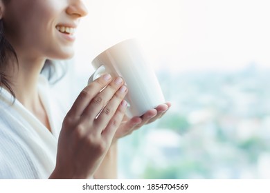 Drinking coffee in the morning, beautiful woman holding cup of coffee and enjoy drinking hot coffee in the morning with smile face and look at nice view. lifestyle concept
