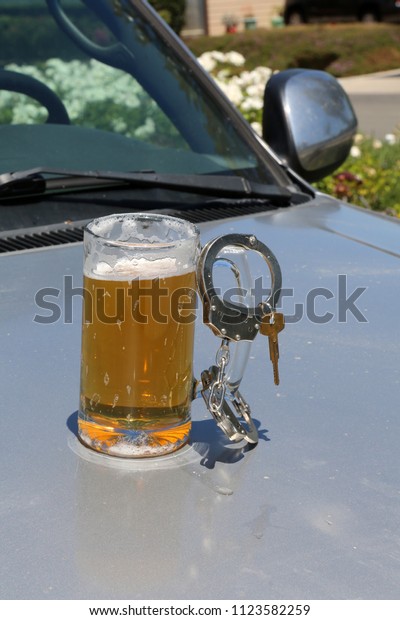 Drinking and Driving concept. DUI Concept. Beer Mug with\
Beer, Hand Cuffs and Car Keys. Driving while intoxicated concept.\
