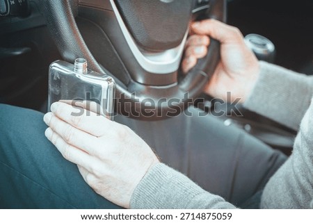 Drinking and driving, drunk driver, sobriety check of drivers. A man is driving a car, holding a bottle of alcohol in one hand and the steering wheel in the other. Road safety concept
