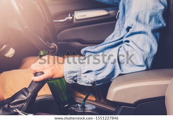 Drinking and driving ,man drinking alcohol and\
using mobile phone while driving car ,concept drive safely while\
using a cell phone or drunk\
alcohol