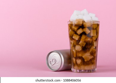 Drinking Glass Of Of Lump Sugar Cubes And Soft Cola Drink With Aluminum Can On Pink Pastel Background. Unhealthly Diet With Sweet Sugary Soft Drinks Concept.