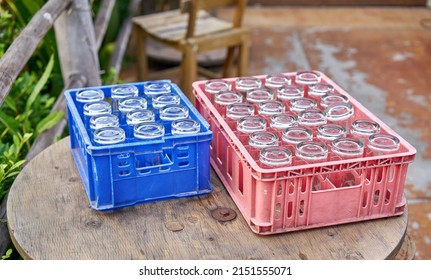 Drinking glasses in crates on an old wooden table at an outdoor cafe.              