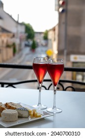 Drinking of Kir Royal,  French aperitif cocktail made  from creme de cassis topped with champagne, typically served in flute glasses, with view on old French village