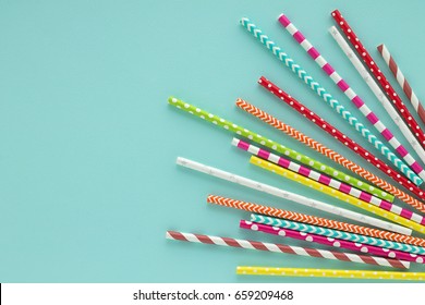 Drinking paper colorful straws for summer cocktails on light blue background with copy space. Top view.