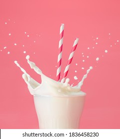 drinking straws into a glass of splashing milk isolated on pastel pink background - Shutterstock ID 1836458230