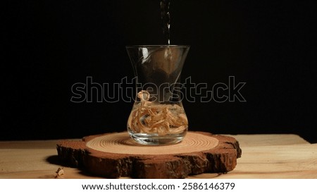 Drinking tea from Magic Psychedelics Mushrooms preparation. Close-up of pouring hot water into a teacup with dry Psilocybin shrooms tea stems on a wooden table. Microdosing for Depression and anxiety.