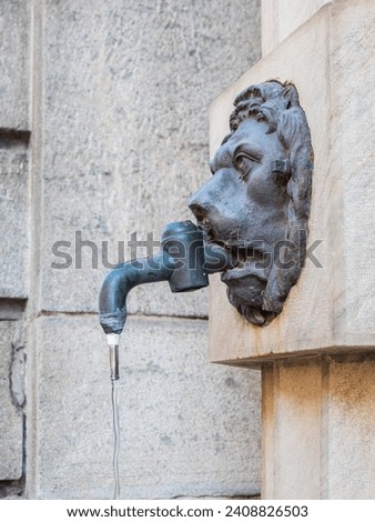 Drinking water in the city with a lion's bronze head tap for hot summer days in Italy in high summer season