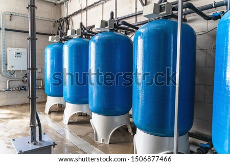 Drinking water factory or plant production, industrial interior. Large metal tanks for filtering and potable water treatment from well.