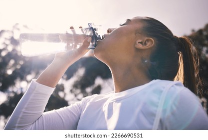 Drinking water, fitness and running with a sports woman outdoor for a cardio or endurance workout. Training, exercise and wellness with a female athlete taking a drink for hydration on a break - Powered by Shutterstock