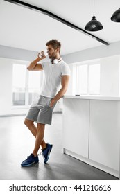 Drinking Water. Handsome Young Man With Sexy Fit Body Drinking Fresh Water From Glass In Morning. Thirsty Fitness Male Model Enjoying Refreshing Drink Indoors. Healthy Nutrition Concept