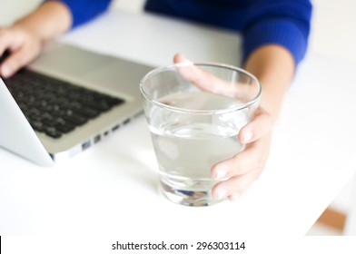 Drinking water while working with laptop computer - Powered by Shutterstock