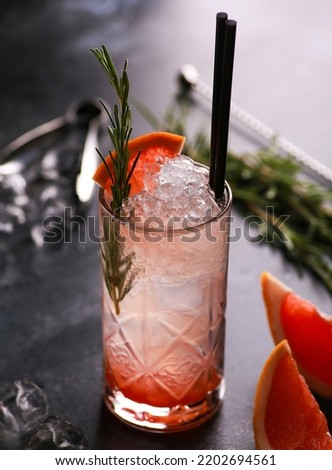 Drinks and cocktails. Beverage light red and white with grapefruit, rosemary and ice in a glass on a black table. Bar menu. Background image, copy space