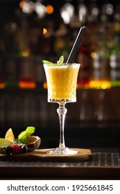 Drinks and cocktails. Orange beverage in a clear glass on the bar table. Mint, passion fruit, fresh berries, lime and orange next to the glass. Restaurant menu, background image, vertical