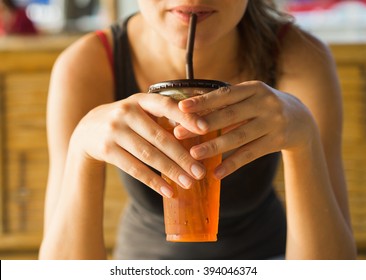 drinks, people and lifestyle concept - close up of  woman drinking ice tea  from plastic cup with straw at cafe