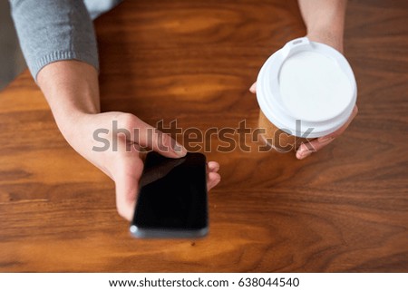 drinks, people, technology and lifestyle concept - close up of woman with smartphone and coffee at table