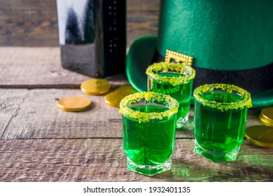 Drinks for St. Patrick's Day party. Good luck leprechaun shot cocktail. Green strong drink in a shot glass with gold decor.