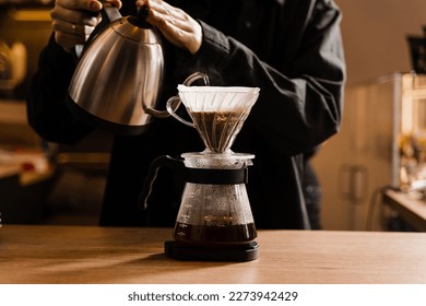 Drip filter coffee brewing. Barista pouring hot water over filter with ground coffee in the funnel. Pour over alternative method of pouring water over ground coffee beans contained in filter - Shutterstock ID 2273942429