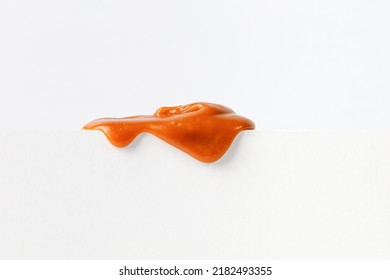 Dripping caramel drops of sweet caramel sauce on white podium on white background.  Melted caramel sauce drip, drops of sweet liquid toffee. - Shutterstock ID 2182493355