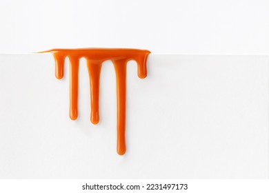 Dripping caramel drops of sweet caramel sauce isolated on white background. Melted caramel sauce drip, drops of sweet liquid toffee.