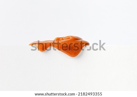 Dripping caramel drops of sweet caramel sauce on white podium on white background.  Melted caramel sauce drip, drops of sweet liquid toffee. Stockfoto © 