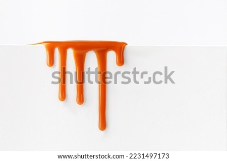 Dripping caramel drops of sweet caramel sauce isolated on white background. Melted caramel sauce drip, drops of sweet liquid toffee.