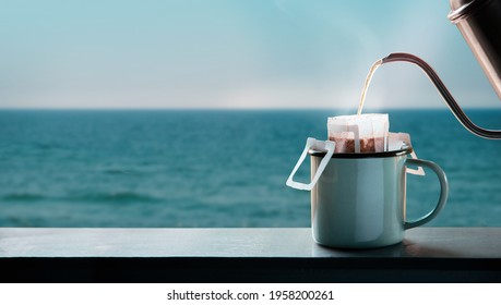 Dripping Coffee by the Sea Side at Morning. Making Hot Drink by Pouring Hot Water from kettle into an Instant Coffee Drip Bag at the Balcony. Relaxing, Enjoying with Harmony Living Lifestyle