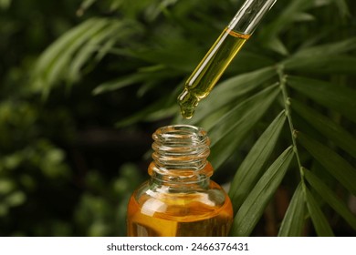 Dripping essential oil from pipette into bottle outdoors, closeup - Powered by Shutterstock