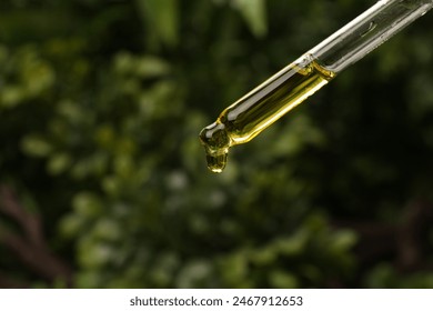 Dripping essential oil from pipette outdoors, closeup - Powered by Shutterstock