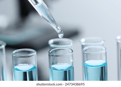 Dripping liquid from pipette into test tube on blurred background, closeup - Powered by Shutterstock