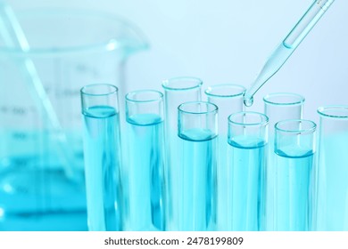 Dripping liquid from pipette into test tube on blurred background, closeup. Laboratory analysis - Powered by Shutterstock