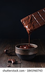 Dripping melted chocolate bar into ceramic bowl on dark background - Shutterstock ID 1841960743