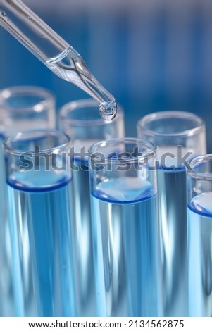 Dripping reagent into test tube on blurred background, closeup. Laboratory analysis