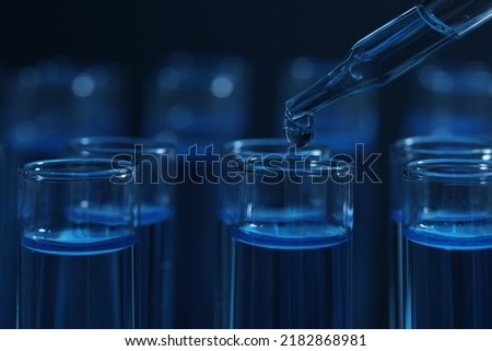 Dripping reagent into test tube with blue liquid on dark background, closeup. Laboratory analysis