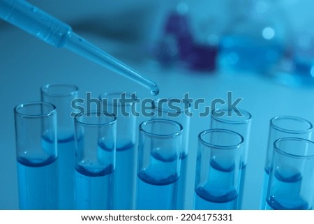 Dripping reagent into test tube with blue liquid, closeup. Laboratory analysis
