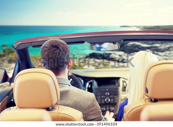 drive, auto trip, travel, tourism and people\
concept - close up of couple driving in cabriolet car from back\
over sea shore\
background