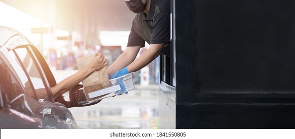 Drive through and takeaway for buy fast food for protect covid19. New normal life style. The staff woman wearing medical glove and mask and handed a food to customer. Drive thru and take away concept. - Shutterstock ID 1841550805