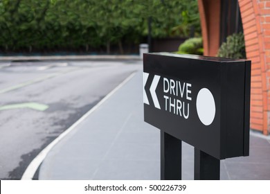 Drive thru sign with shop and road background.