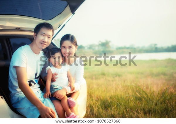 drive in the\
vacations family; asian family are happy sitting in the open trunk\
of a car; travel nature\
trip.