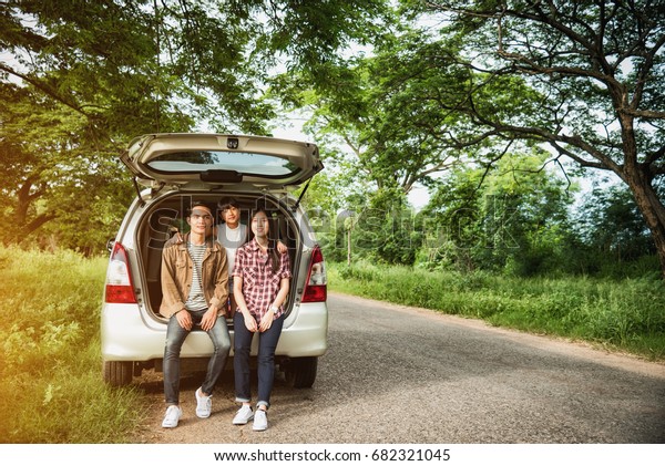 drive in the\
vacations family; asian family are happy sitting in the open trunk\
of a car;  travel nature\
trip.