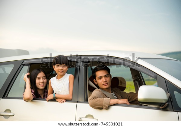 drive in the\
vacations family; Asian family are happy sitting in the open trunk\
of a car;  travel nature\
trip.