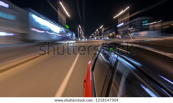 Drivelapse from side of fast car\
moving on a night avenue in a city timelapse hyperlapse, road with\
lights reflected on car at high speed. Rapid rhythm of a modern\
city.