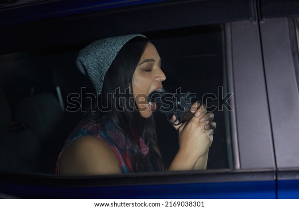 Driven to the extreme. Shot of a\
young woman sitting in a car and pointing a gun into her\
mouth.