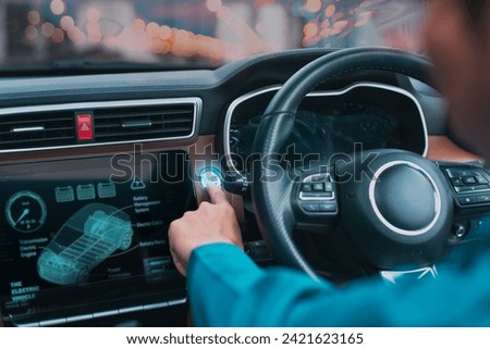 Driver activating start button on an electric car's interactive dashboard at dusk.