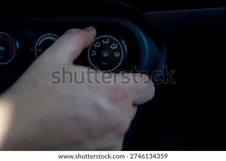 Driver adjusting airflow direction control on car climate panel, close up of ventilation mode selector inside vehicle interior.