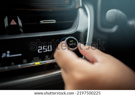 Driver adjusting car air conditioner system at interior panel. Car control panel showing temperature and human fingers turning button hot and cool for comfortable.