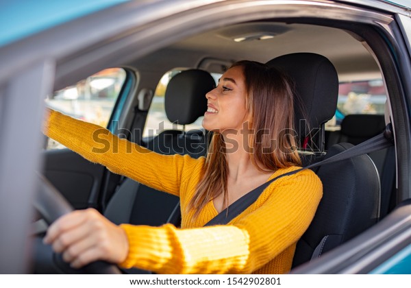 Driver adjusting the Rear Mirror looking at\
herself. Adjusting the rear view mirror. Woman adjusts the rear\
view mirror with her hand. Happy young woman driver looking\
adjusting rear view car\
mirror