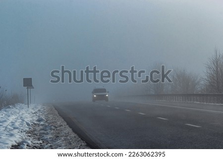 Driver of almost empty grey foggy misty rainy highway intercity road with low poor visibility on cold spring autumn morning. Seasonal bad rainy weather accident danger warning. car fog light.