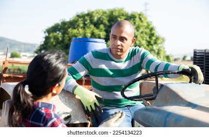 Driver and assistant opestanding near tractor in garden - Shutterstock ID 2254134223
