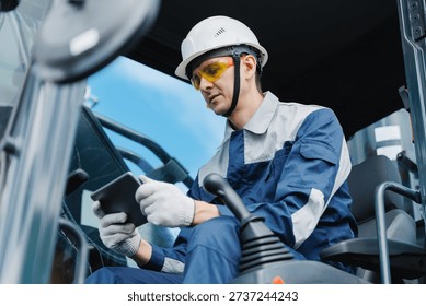 Driver builder operate excavator use tablet computer at construction site, technology inIndustry work.