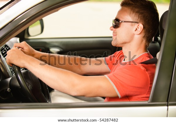 Driver of\
car in dark sun glasses at wheel in\
profile.